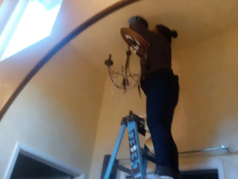 Electrician installing a chandelier in a Inverness residence